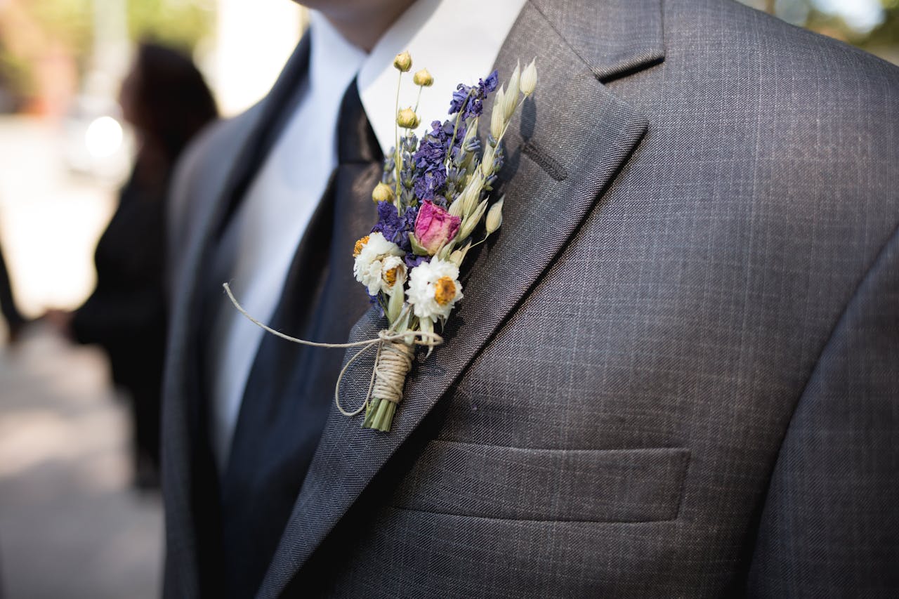 Close-up of an elegant groom wearing a designer suit and floral boutonniere during a wedding ceremony.