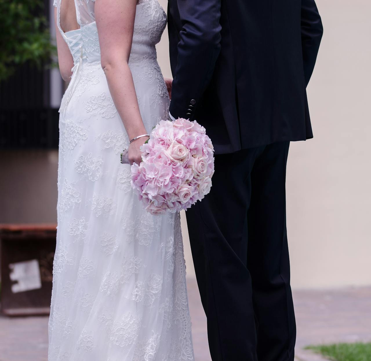 Bride and groom holding a pink rose bouquet, showcasing love and elegance in a wedding setting.